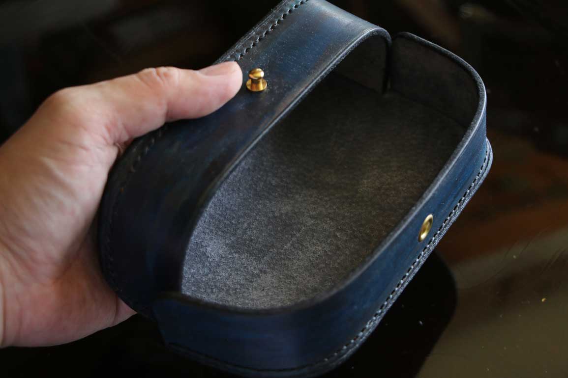 一点物のThe Crescent Moon Glasses case。ターコイズブルーからネイビーへと移ろうグラデーションに、深紅のアクセントを重ねた本革メガネケース。内装には起毛革を使用した三日月型デザイン。